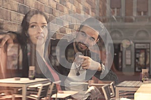 Young woman man sitting caffee shop window reflection