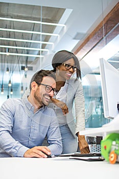 Young woman and man working together on desktop pc in the modern office