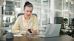 Young woman manager records a podcast, lecture, or webinar on a dictaphone.