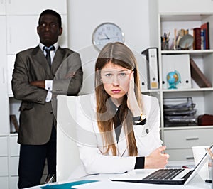 Young woman manager sitting at table after conflict, angry man boss