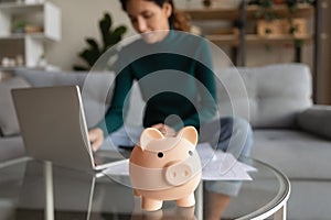 Young woman managing household budget at home office using laptop