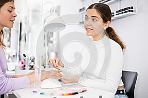 Young woman manicure master shaping nails to female client