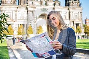 Young woman with map searching for city attraction outdoors.