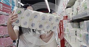 Young woman in a mask from a coronavirus epidemic buys toilet paper in a supermarket, where people panicky buy