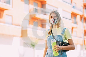 Young woman in a mask drinking water and walking around the city. Way of life, new normality, covid