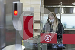 A young woman in a mask enters the subway through the turnstile. Coronavirus pandemic and security