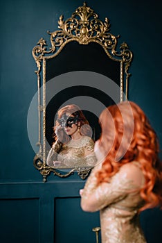 Young woman in mask looks in mirror