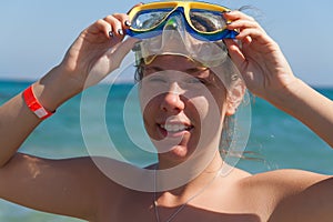 A young woman in a mask for scuba diving laughs, a large portrait. The concept of a hilarious and excellent holiday on the beach