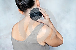 Young woman massages her back with spiky trigger point ball, muscle pain treatment reflexology. Physiotherapy concept