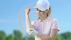 Young woman massaging bruised elbow after golf tournament, professional injury