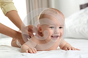Young woman massaging cute little baby on bed