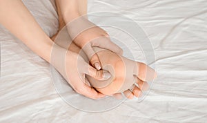 Young woman massaging her foot on the bed., Healthcare concept