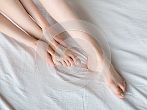 Young woman massaging her foot on the bed. Healthcare concept