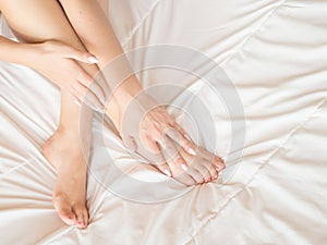 Young woman massaging her foot on the bed., Healthcare concept.