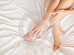Young woman massaging her foot on the bed. Healthcare concept