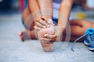 Young woman massaging her painful foot from exercising