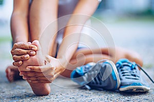 Young woman massaging her painful foot from exercising