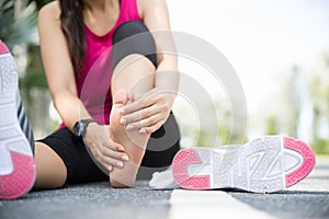 Young woman massaging her painful foot while exercising. Running Sport and excercise injury concept