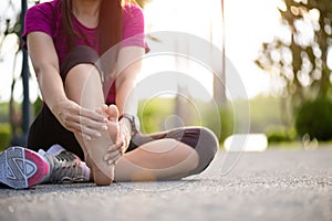 Young woman massaging her painful foot while exercising. Running Sport and excercise injury concept