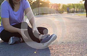 Young woman massaging her painful legs from jogging and running in the park. Sport and exercise concept