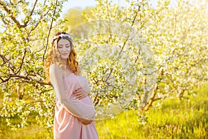 Young woman in maternity pink dress waiting for baby birth.