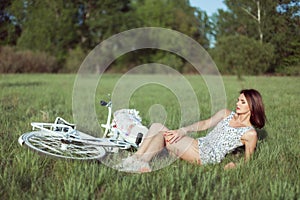 Young woman on a meadow with a bicycle.