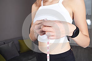 Young woman measures her breast with a measuring tape