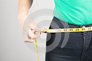 young woman measures her waist with a tape