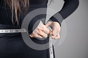 Young woman measuring abdominal circumference with measuring tape