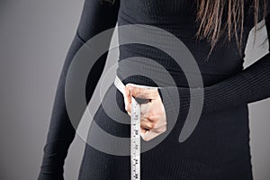 Young woman measuring abdominal circumference with measuring tape