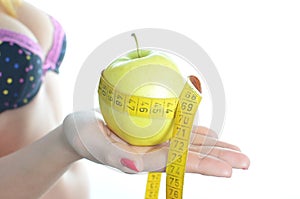 Young woman measuring body holding apple