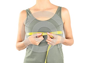 Young woman measuring breast size on white background, closeup.