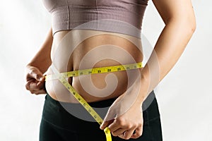 Young woman measuring her excessive belly fat waist with measure tape, woman diet lifestyle concept