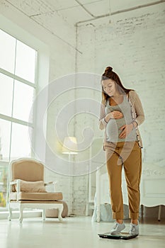Young woman measuring her weight while pregnancy