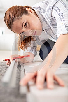 young woman measuring and marking laminate floor