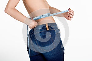 Young woman measuring waist with a tape