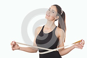 Young woman measuring waist with tape measure