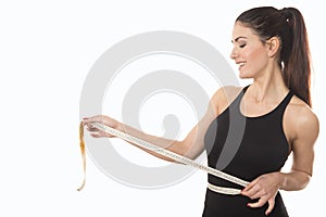 Young woman measuring waist with tape measure