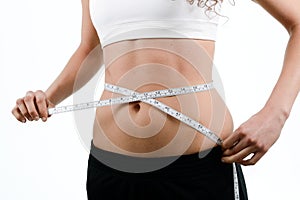 Young woman measuring waist with tape on white background