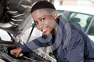 Young woman mechanic repairing a car.