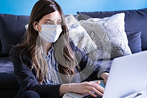 Young woman with medical face mask working from home. Business woman doing home office for coronavirus situation. Covid-19