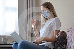 Young woman in medical mask doing video call with collegues from home during self isolation and quarantine