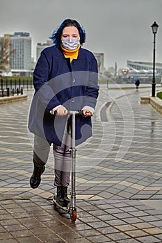 Young woman in medical mask rides a scooter photo