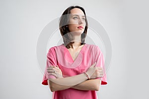 Young woman medical professional nurse or doctor dressed with pink hospital clothes looking confident hero-shot