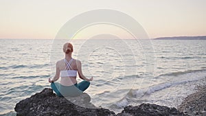 Young woman meditate in front of orange sunset