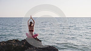 Young woman meditate in front of orange sunset