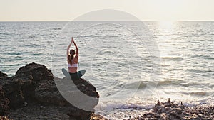 Young woman meditate in front of orange sunset