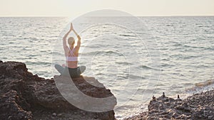 Young woman meditate in front of orange sunset