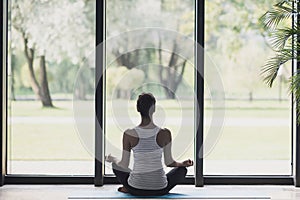 Young woman meditate at home, Girl practicing yoga near floor window in yoga studio, Relaxation, body care concept