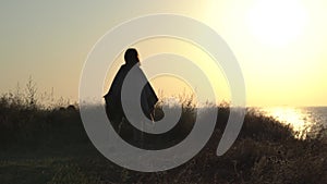 Young woman meditates, dances and whirls at sunrise, sunset on the seashore. Silhouette of a woman, meditation, relaxation, vacati